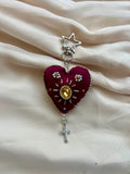 Heart-shaped pendant with star and cross on a beige fabric background