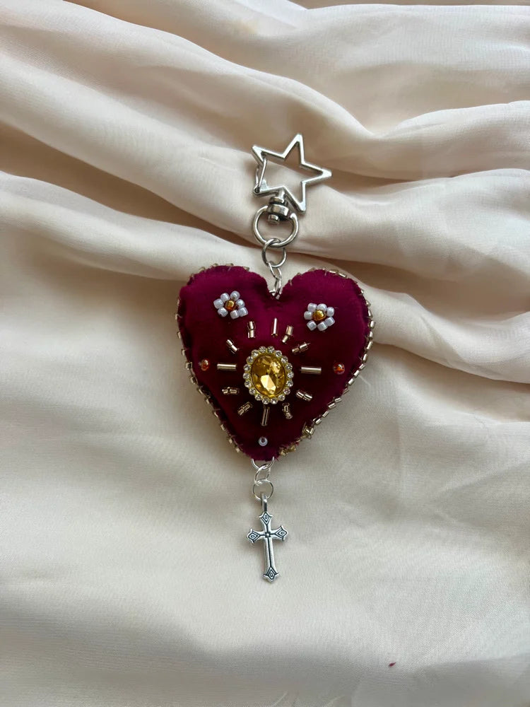 Heart-shaped pendant with star and cross on a beige fabric background