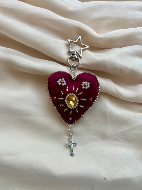 Heart-shaped pendant with star and cross on a beige fabric background