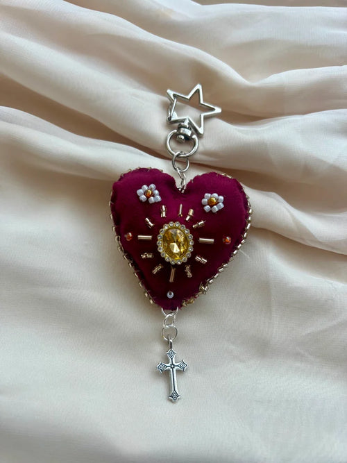 Heart-shaped pendant with star and cross on a beige fabric background