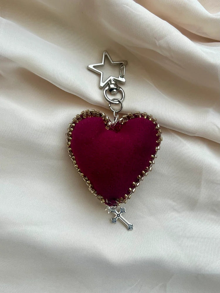 Heart-shaped charm with star and cross on a beige fabric background