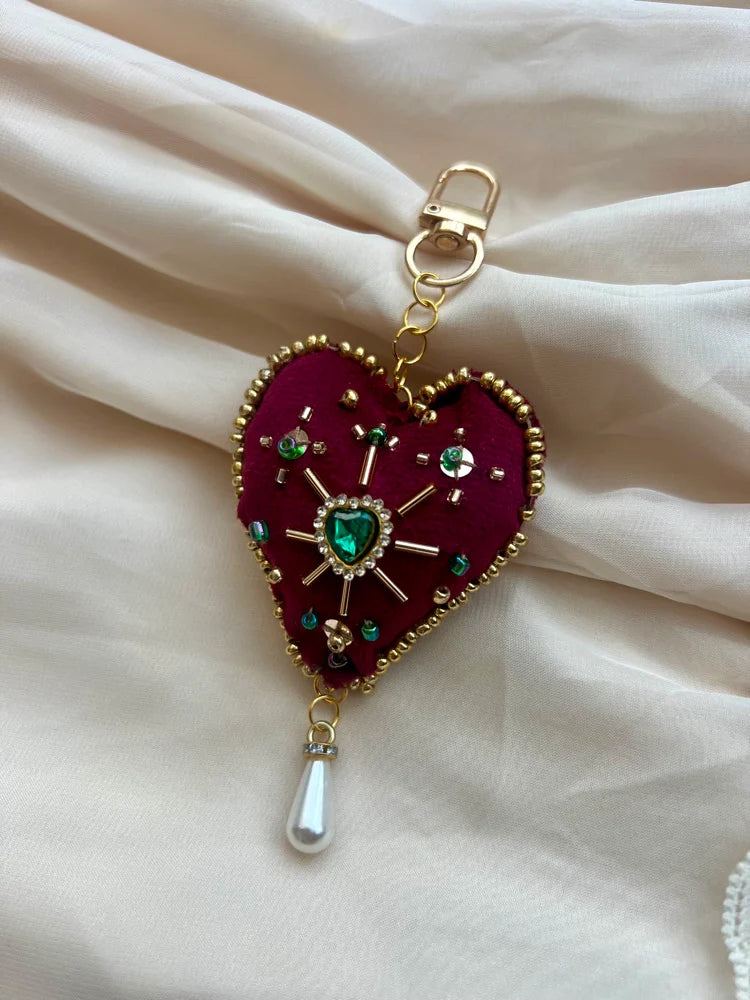 Heart-shaped keychain with decorative elements on a white fabric background