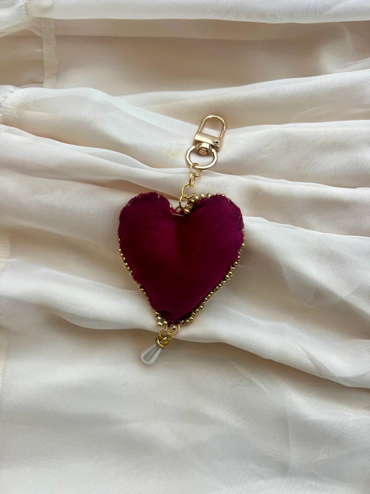 Heart-shaped keychain with gold accents on a white fabric background