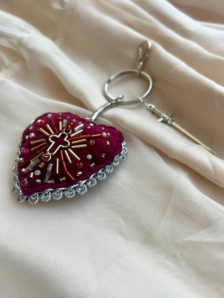 Decorative keychain with heart design and embellishments on a beige fabric background