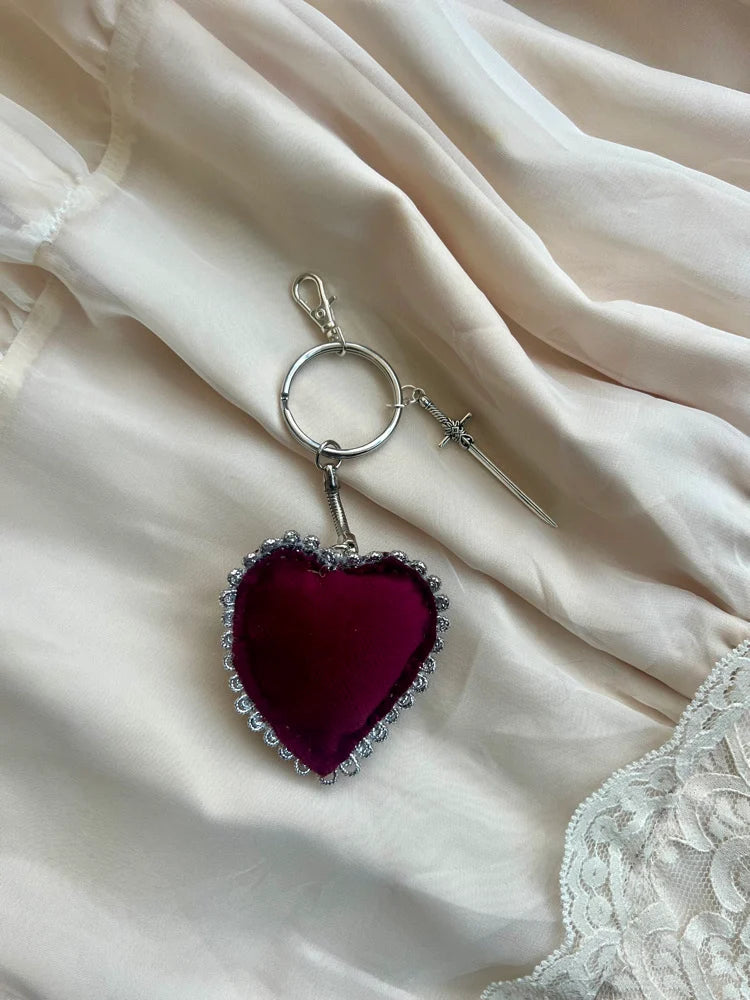 Heart-shaped keychain with a red fabric center on a soft, light-colored fabric background